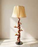 آباژور ایستاده کنارسالنی دستساز با پایه طرح شاخه و پرنده، شید پارچهای کرم و نور گرم در دکوراسیون پذیرایی