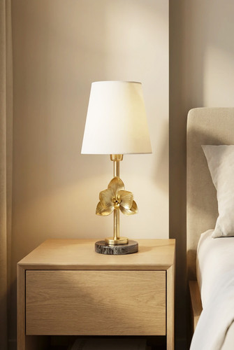 چراغ خواب رومیزی برنجی مدل گل طلایی روی میز چوبی کنار تخت