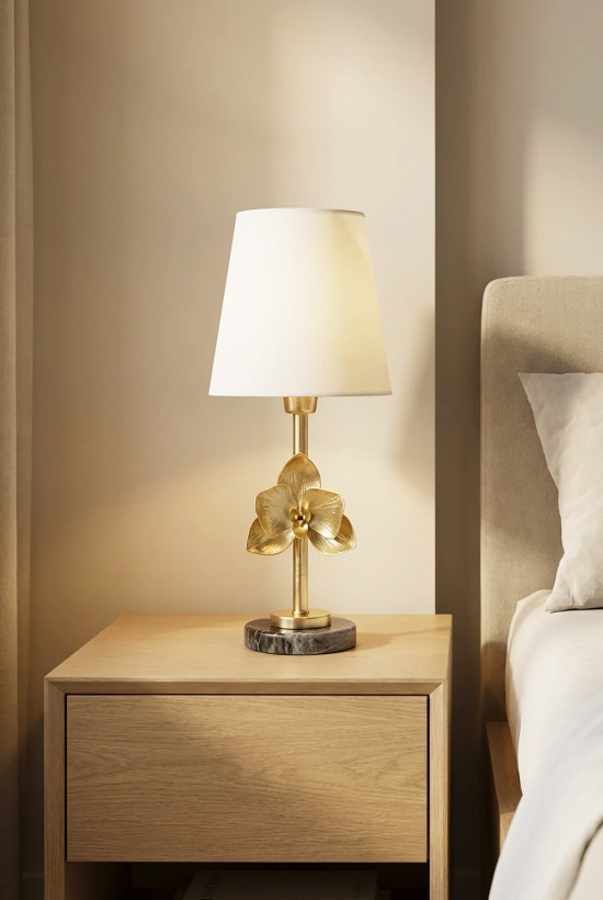 چراغ خواب رومیزی برنجی مدل گل طلایی روی میز چوبی کنار تخت